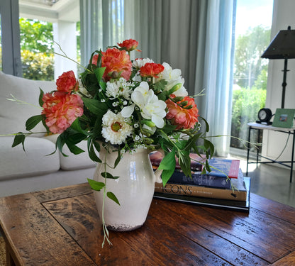 artificial peach ranunculus white freesia white gypsopholia floral arrangement in aged cream ceramic jug 