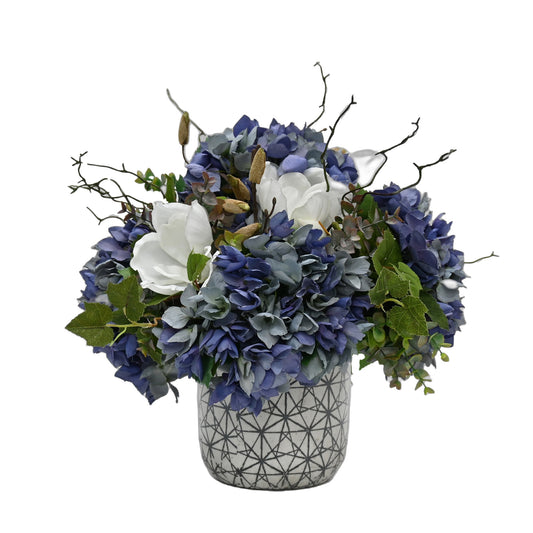 artificial blue and purple hydrangeas white magnolia floral arrangement set into white and black ceramic vase