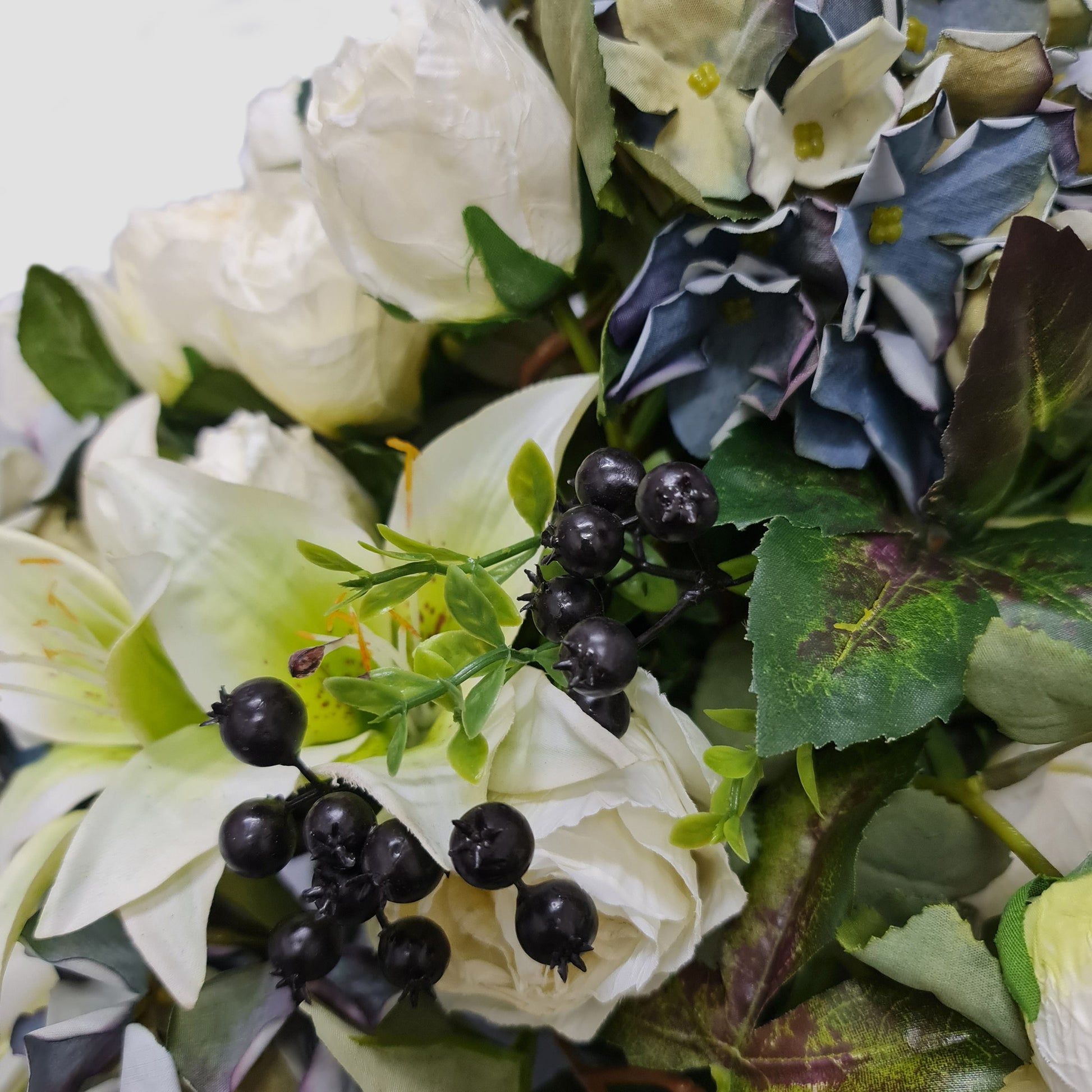 artficial flower arrangement with blue hydrangeas berries and lilies in duckegg ceramic vase