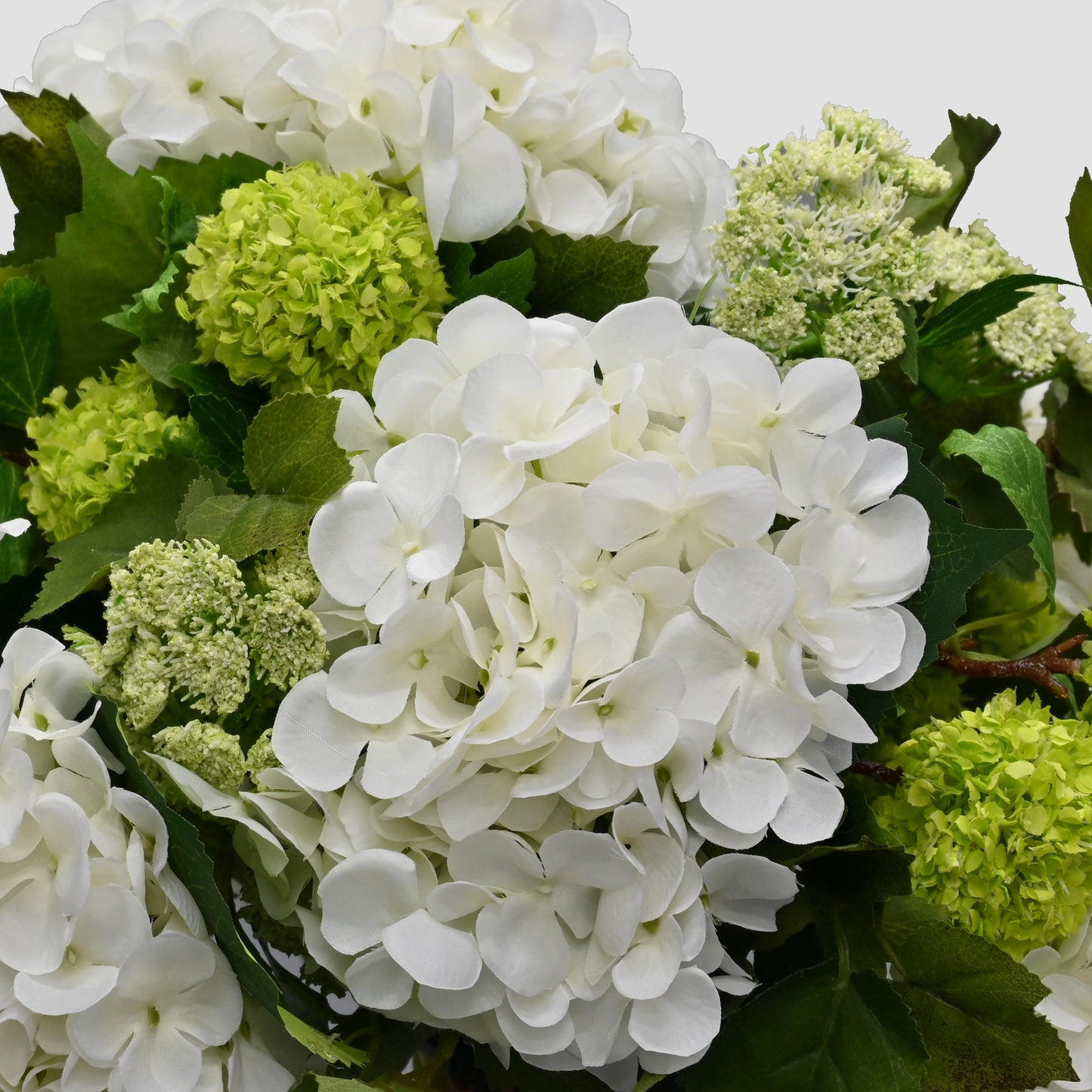 silk floral arrangement set into black rustic tin urn with white hydrangeas and snowball flowers