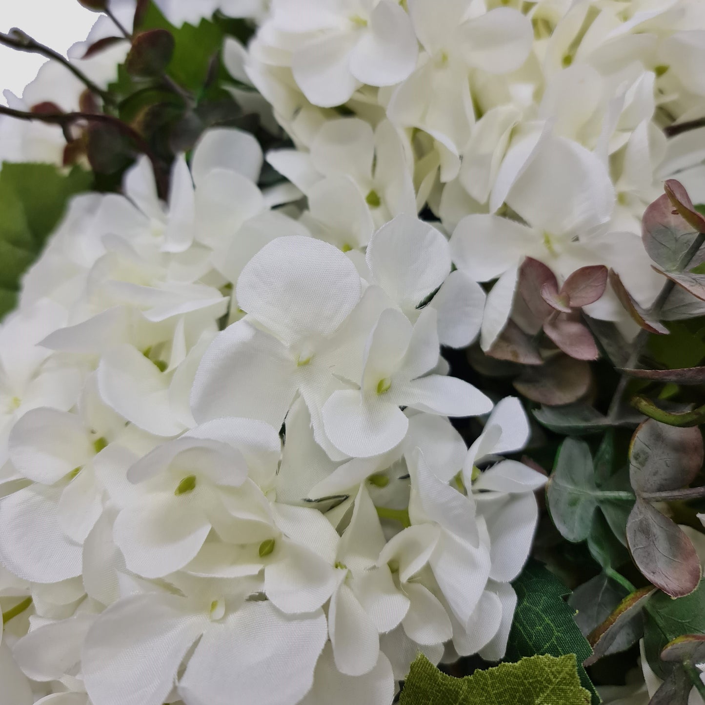 artificial white hydrangeas eucalyptus foliage in aged cream vase