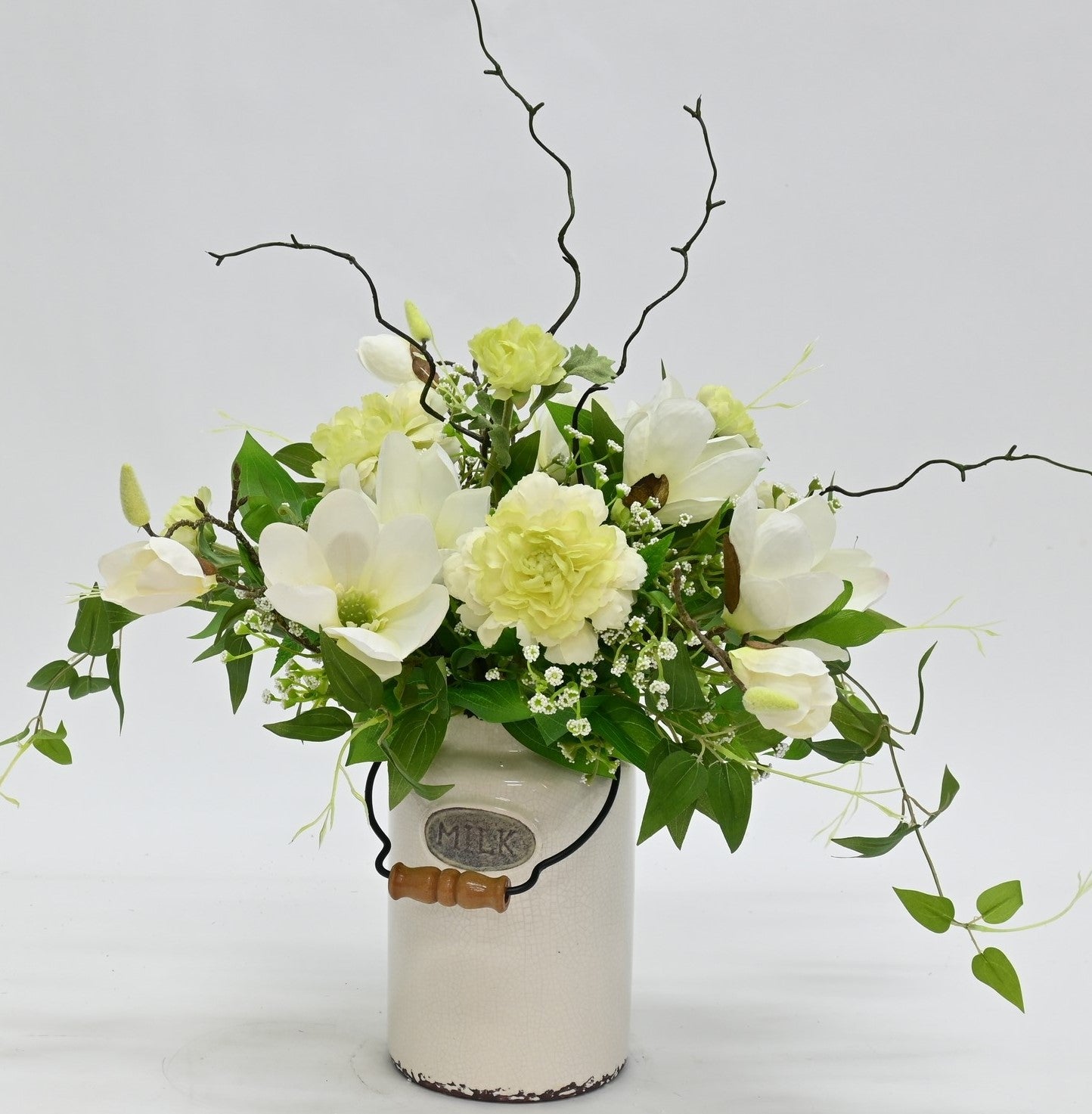 artificial white magnolia white ranunuculus floral arrnangement in aged antique cream milk churn